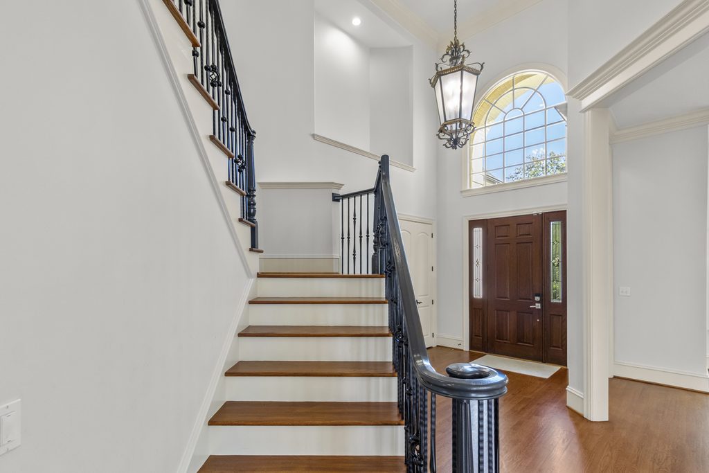Two-story foyer with arched window, iron lantern and curved staircase in a Raleigh, NC home