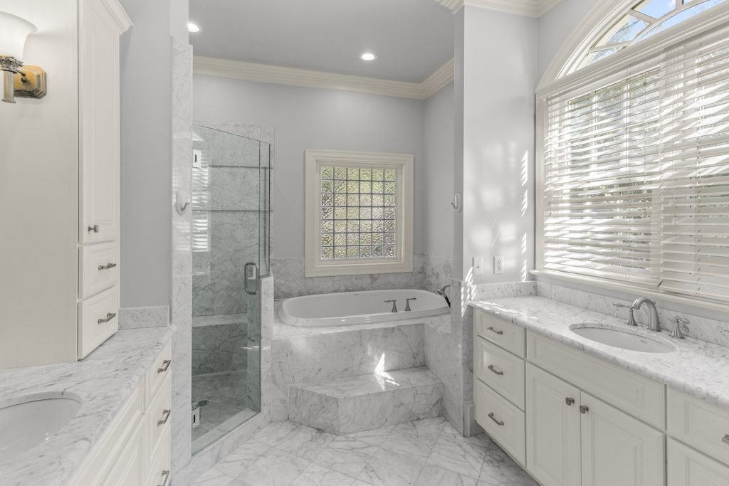 Primary bath with white marble, soaking tub and glass-block window in a Raleigh, NC home